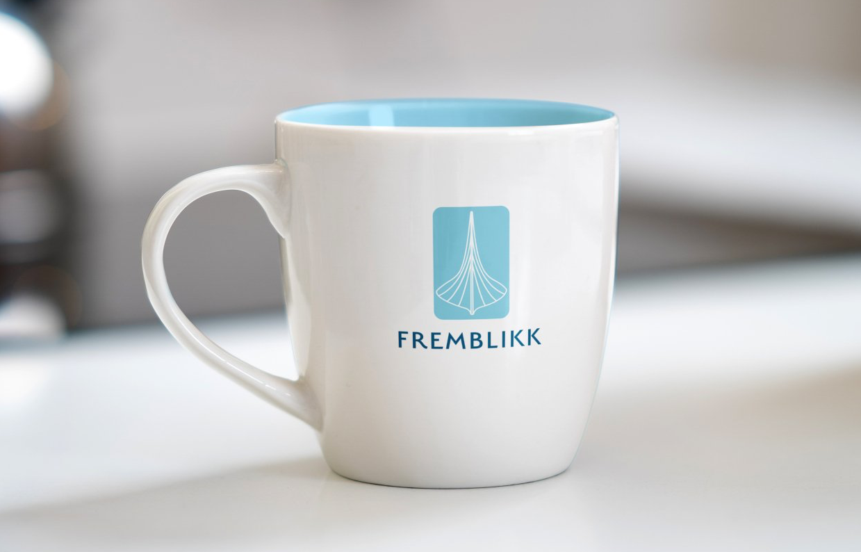 Et hvitt kaffekrus med en blå inni og ordene fremblikk på