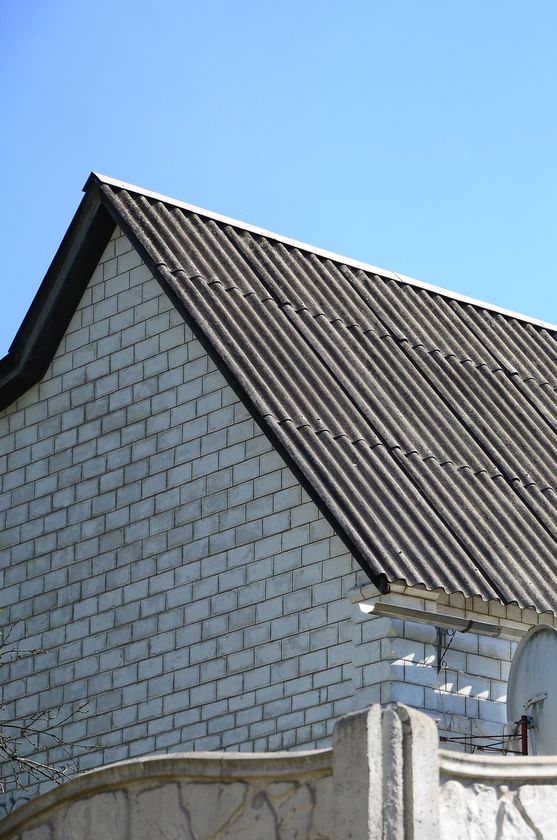 White brick building with corrugated roof against a clear blue sky.