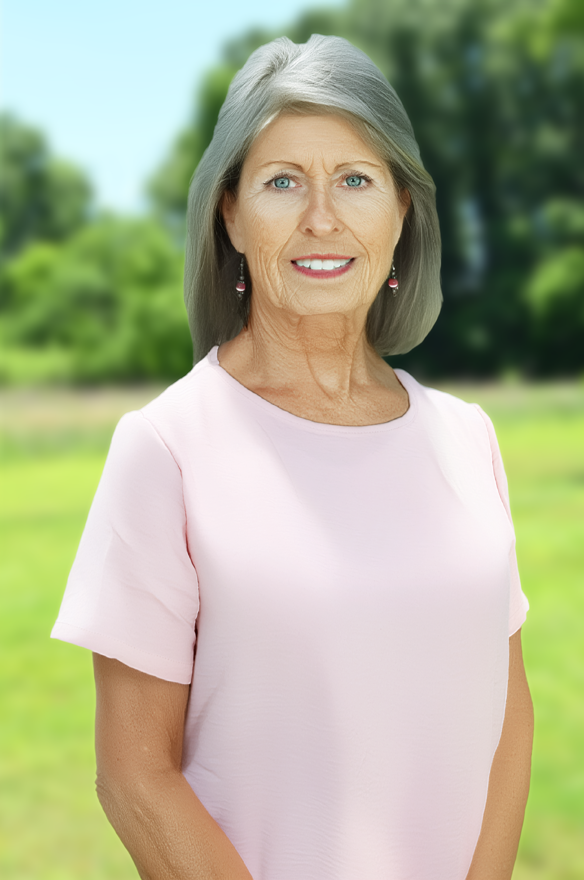 Smiling woman in a pink shirt standing by a pond with a building in the background