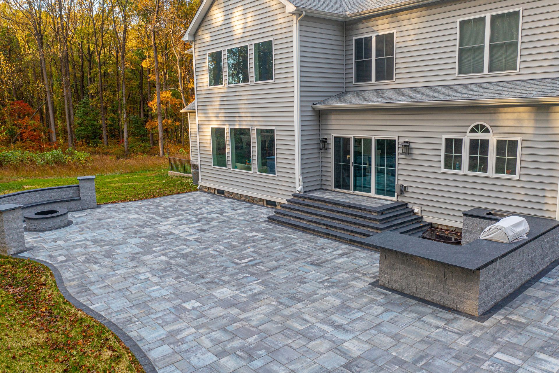 Backyard patio with covered seating area, concrete floor, and raised wooden border beside a house