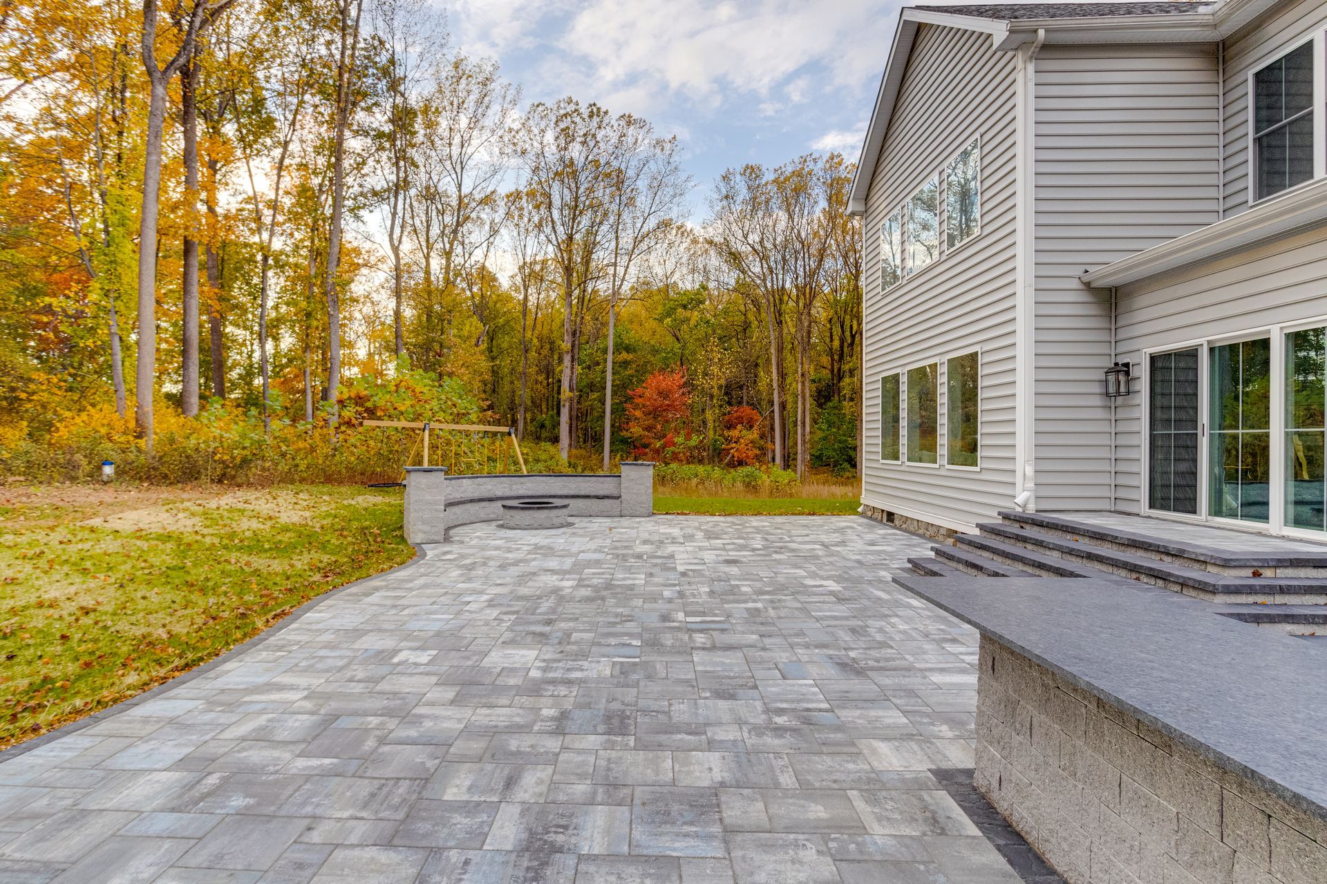 Backyard patio with covered pergola, concrete floor, and raised wooden border beside a house
