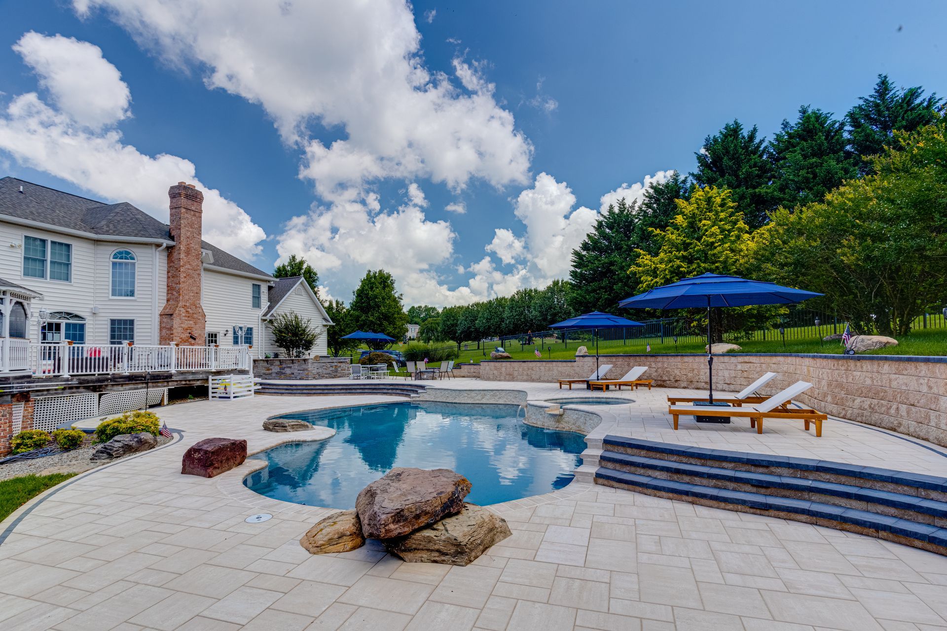 Backyard patio with covered seating area, concrete deck, and raised wood trim beside a house