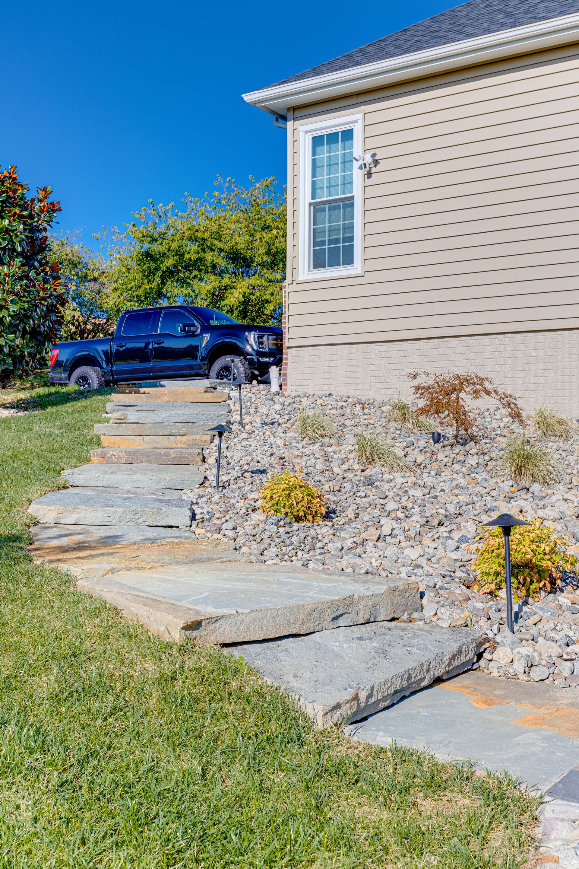 Back patio with covered seating area, concrete floor, and raised wooden deck steps beside a house.