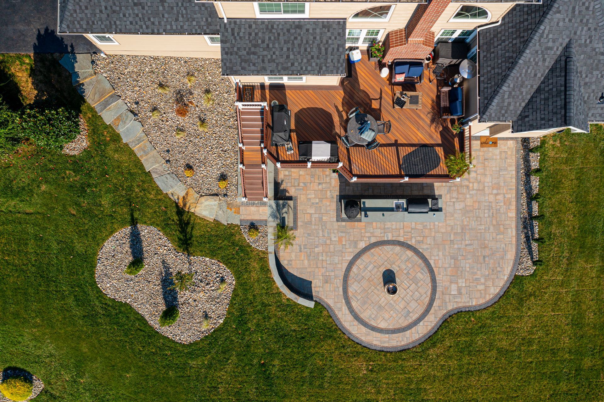 Back patio with covered seating area, concrete floor, and raised wooden deck steps beside a house.