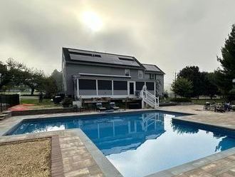 There is a large swimming pool in front of a house.