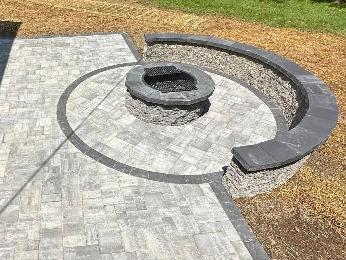 Stone patio with a circular fire pit and curved seating wall.
