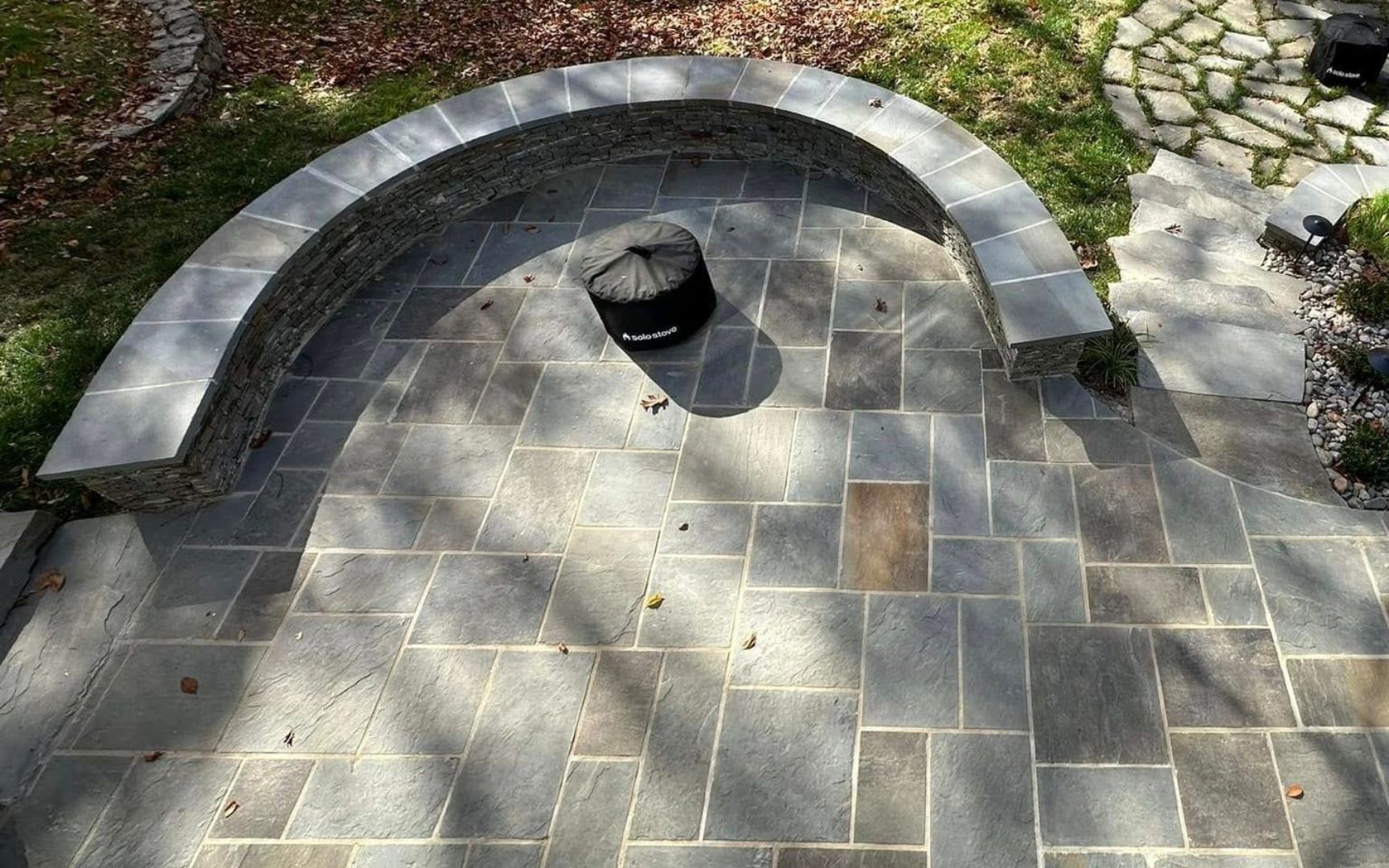 Stone patio with curved stone bench and fire pit.
