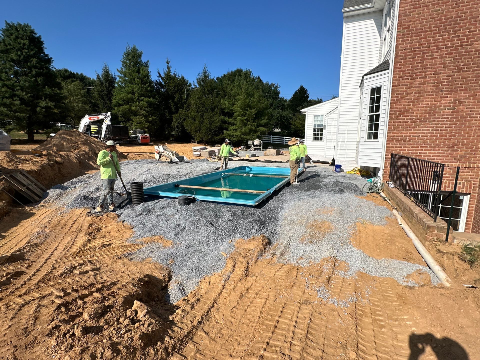 A swimming pool is being built in front of a brick building.