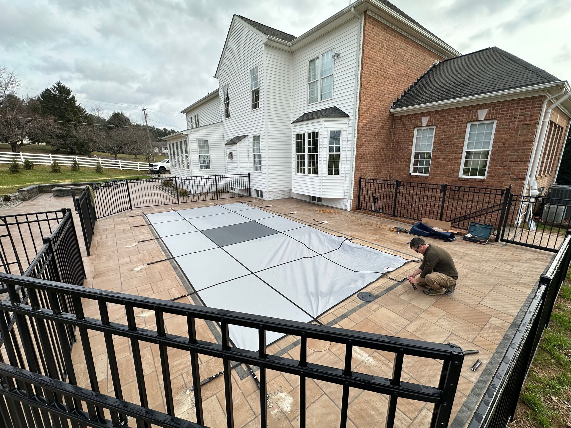 A man is working on a dance floor in front of a large house.