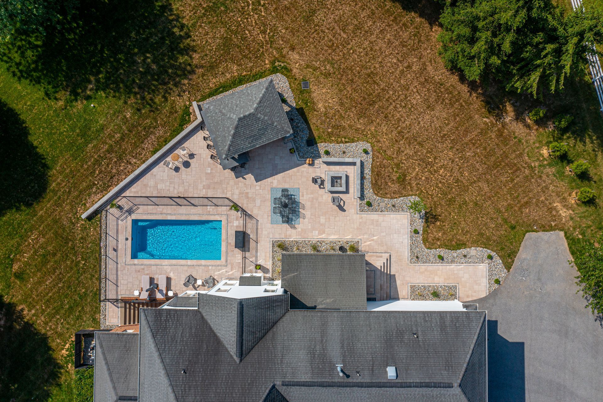 Back patio with covered seating area, concrete floor, and raised wooden deck steps beside a house.