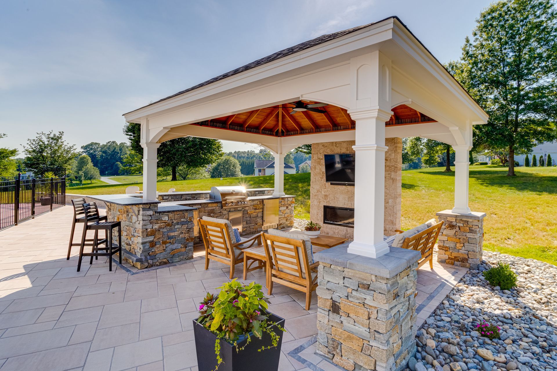 Backyard patio with covered seating area, concrete deck, and raised wood trim beside a house