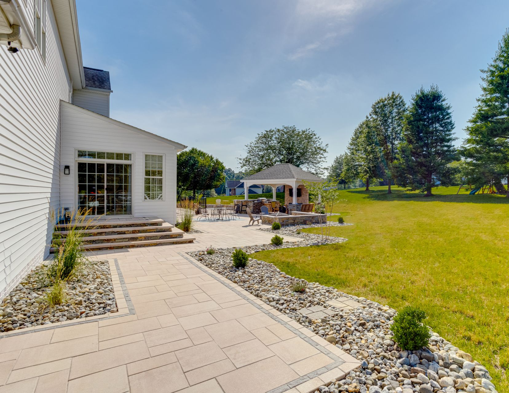 Backyard patio with covered seating area, concrete floor, and raised wooden border beside a house