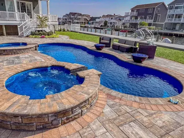 Back patio with covered seating area, concrete floor, and raised wooden deck steps beside a house.