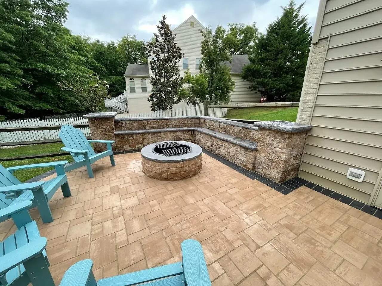 Back patio with covered seating area, concrete floor, and raised wooden deck steps beside a house.