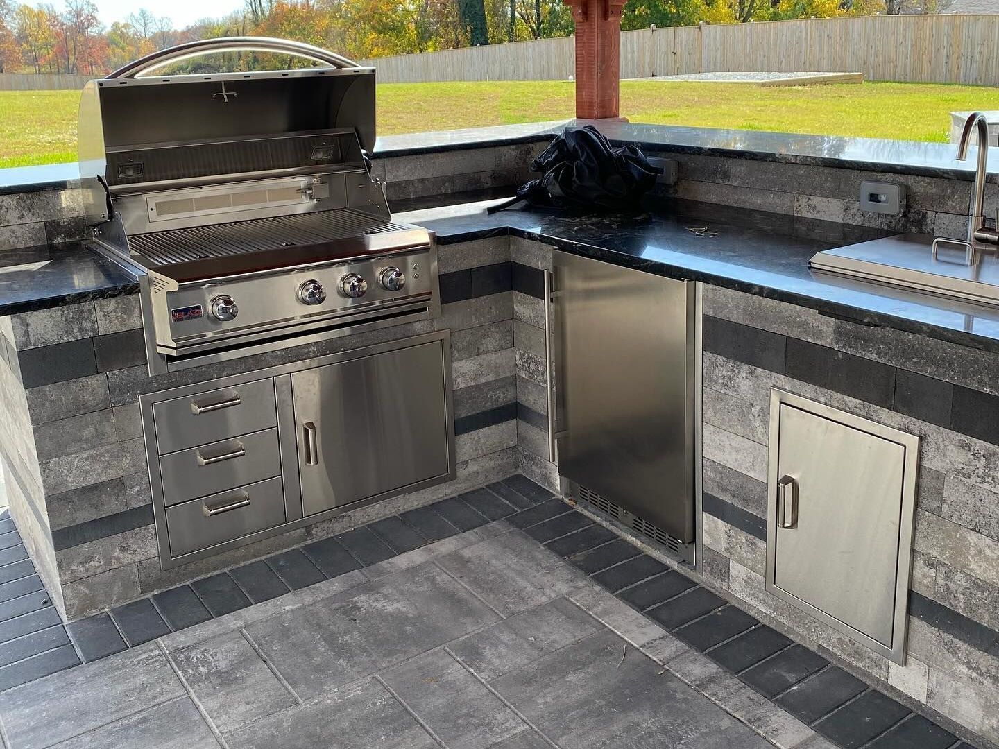 An outdoor kitchen with stainless steel appliances and a grill.