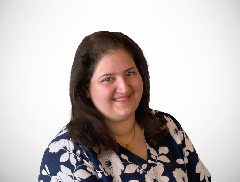 A woman in a blue and white floral shirt is smiling for the camera.
