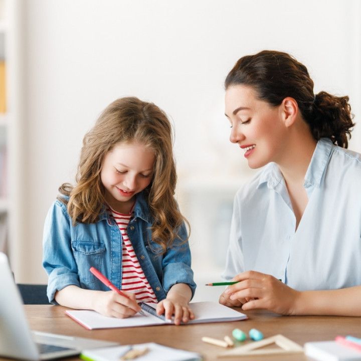 A woman is helping a little girl with her homework.