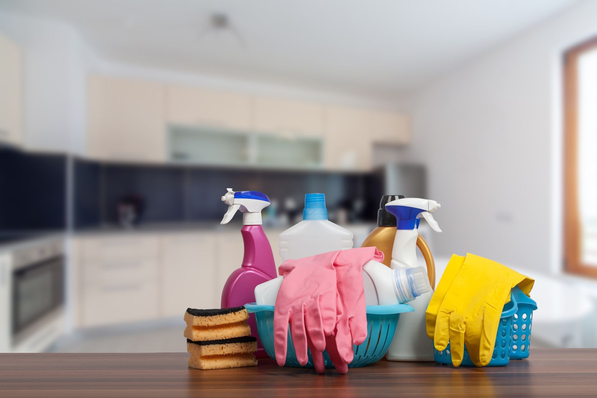 Cleaning supplies are sitting on a wooden table in front of a kitchen.