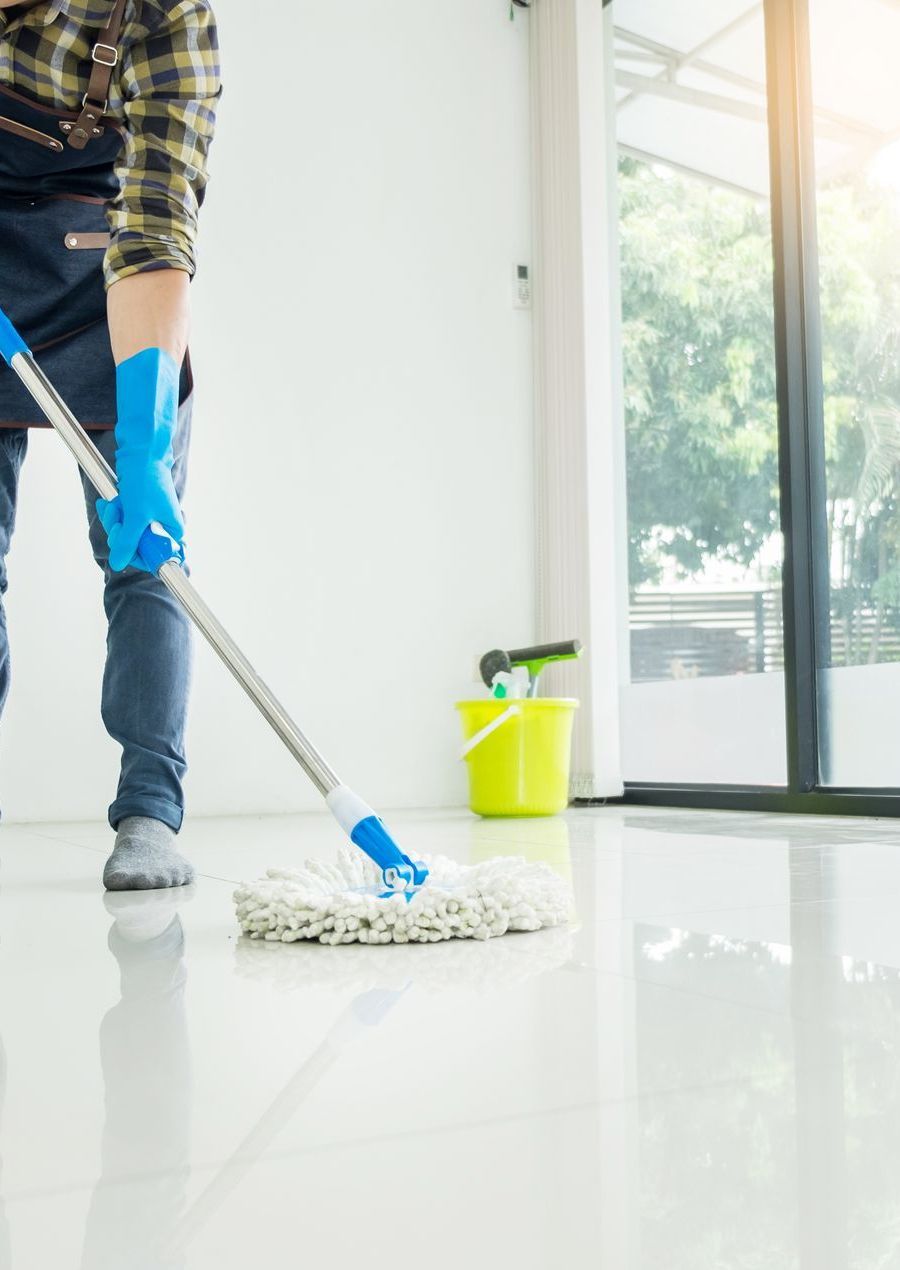 A man is cleaning the floor with a mop in a room.