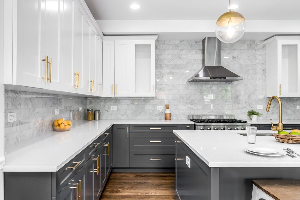 A kitchen with gray cabinets , white cabinets , a stove and a sink.