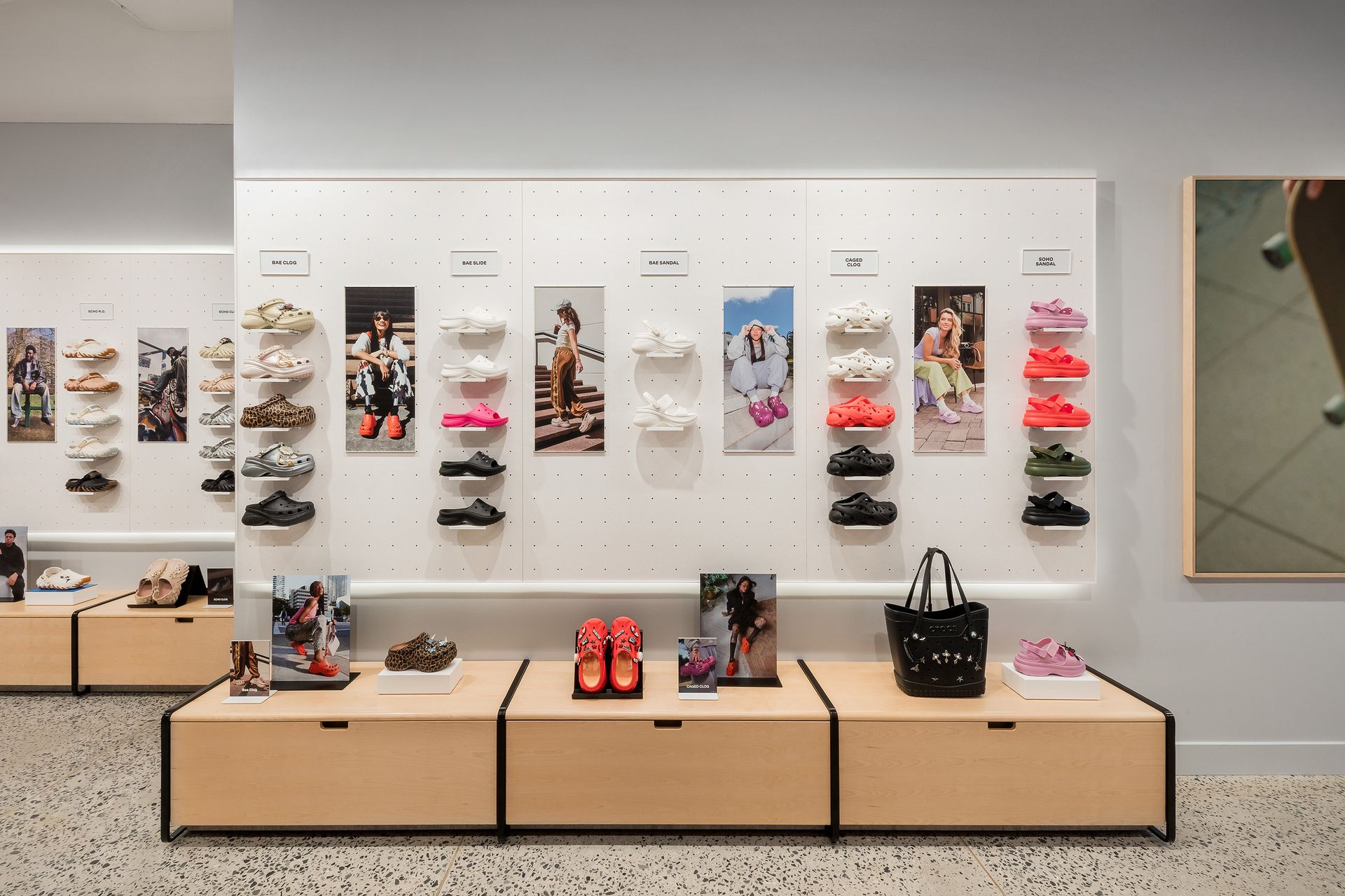 Crocs Shoe display in a store with wooden shelves and a pegboard wall showing various colored Crocs with images.