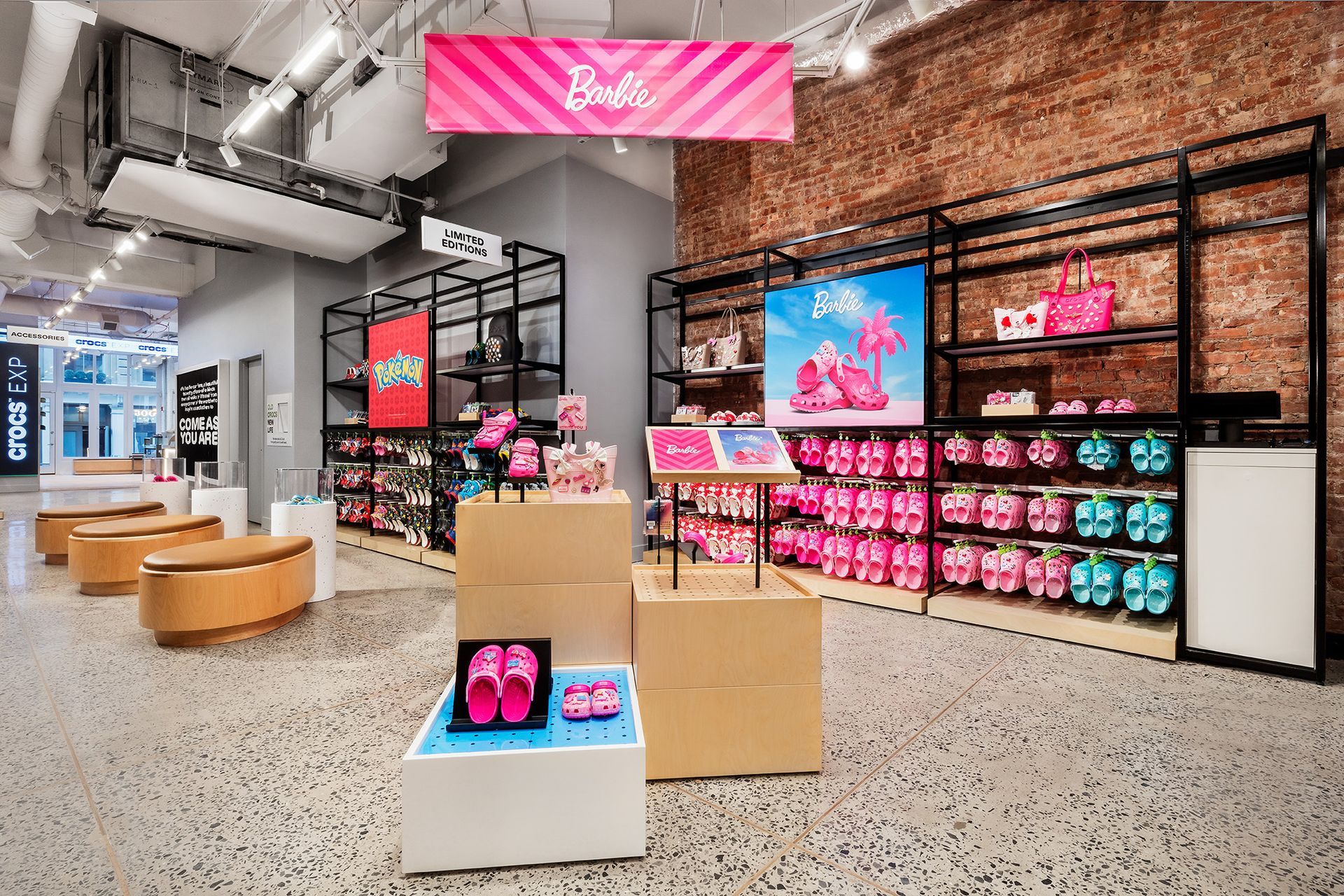 Inside a store, rows of pink and blue sandals are displayed on shelves with a brick wall backdrop.