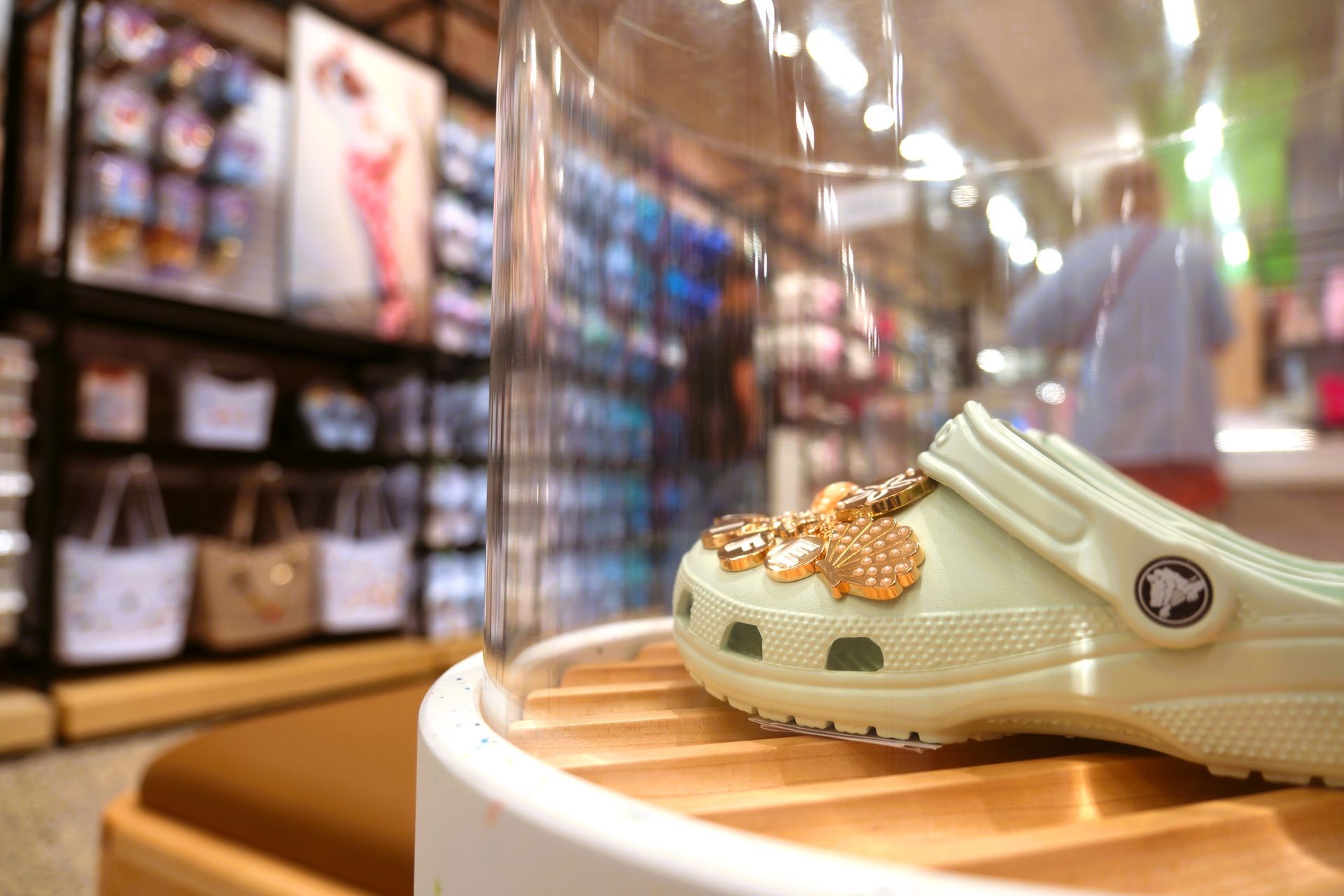 Crocs Shoe store interior: shoes displayed on shelves, wooden benches, bright lighting, and neutral colors.