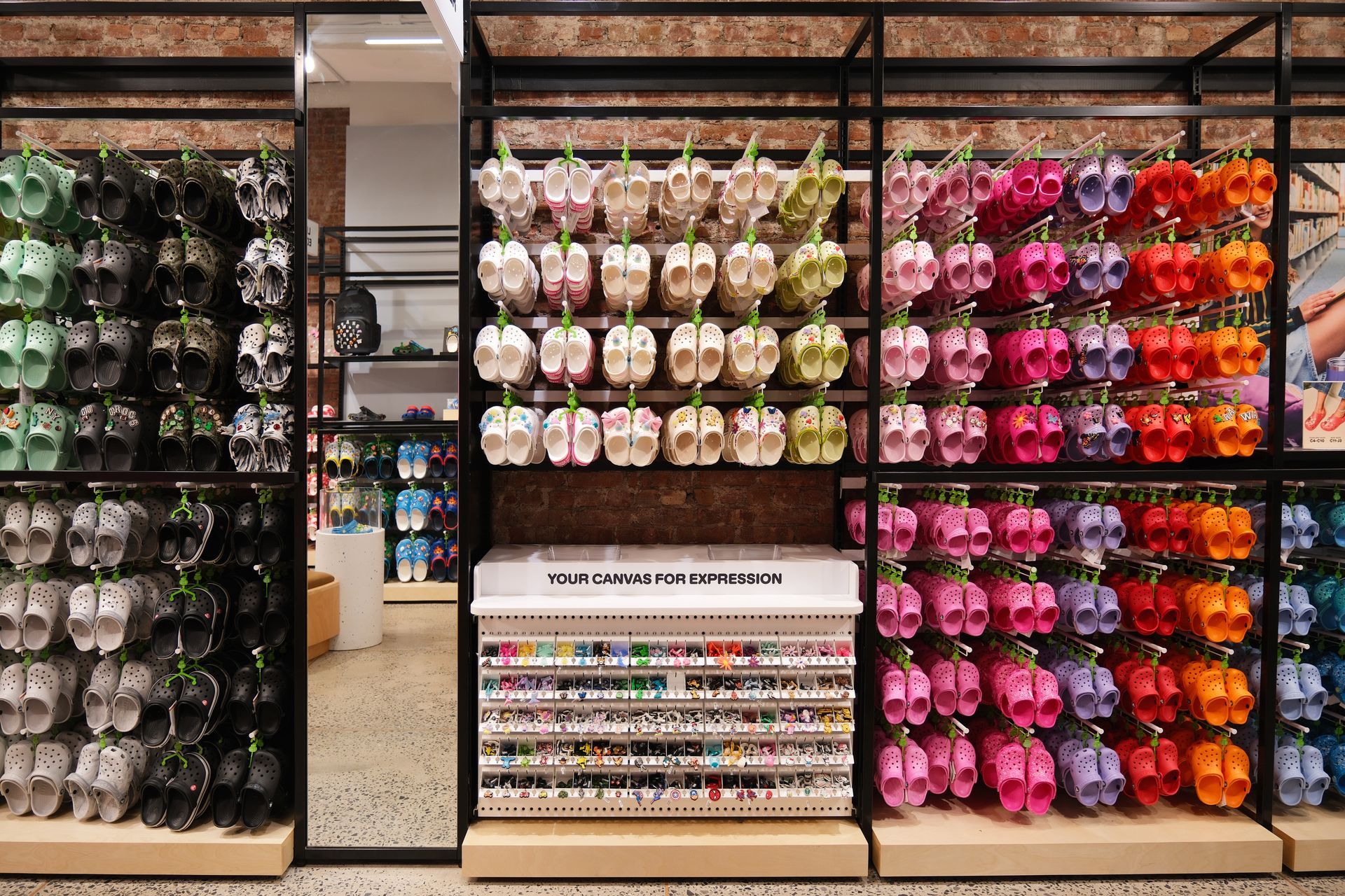 Shoe store display featuring multiple pairs of shoes on wooden shelves and a neutral-colored wall.