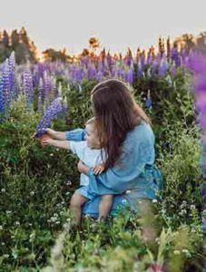 A woman is holding a baby in a field of purple flowers.