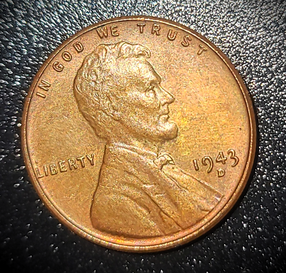 Close-up of a worn 1943 Lincoln wheat penny on a dark textured surface