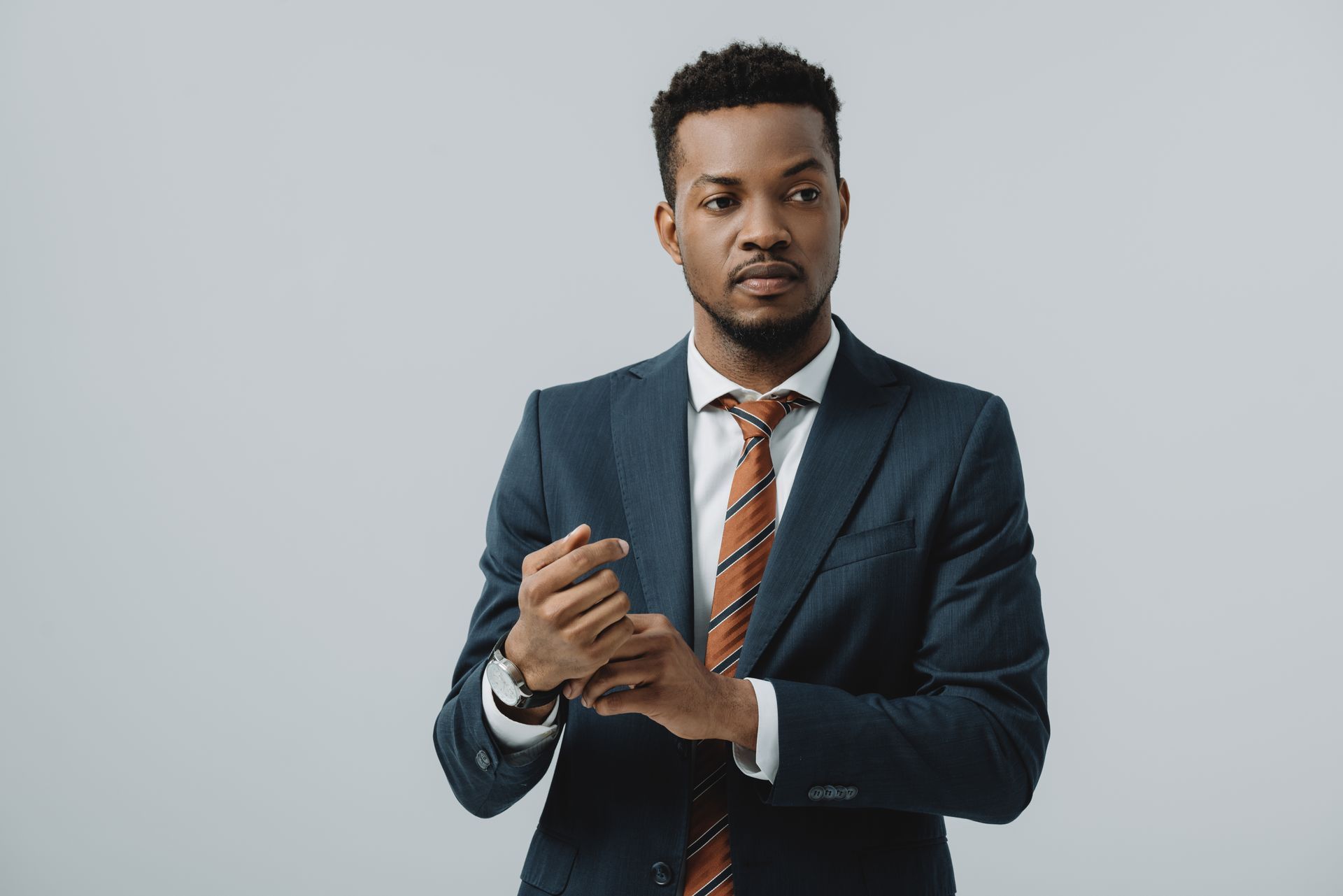 A man in a suit and tie is adjusting his cuffs.
