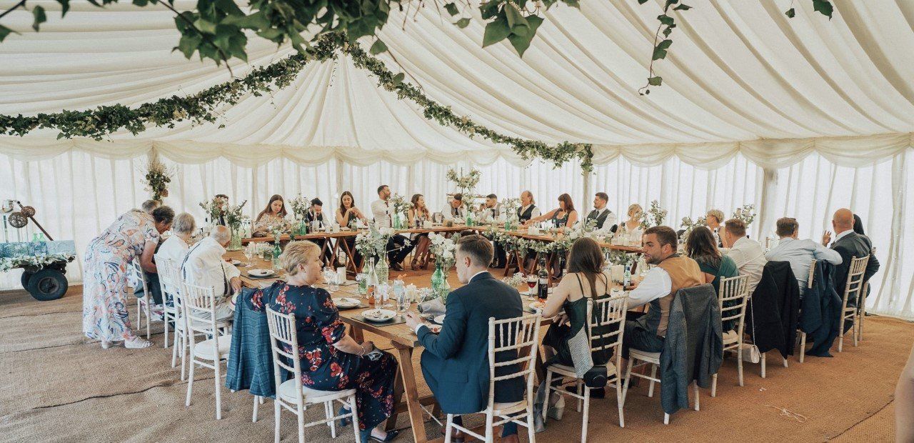 A large group of people are sitting at tables in a tent.