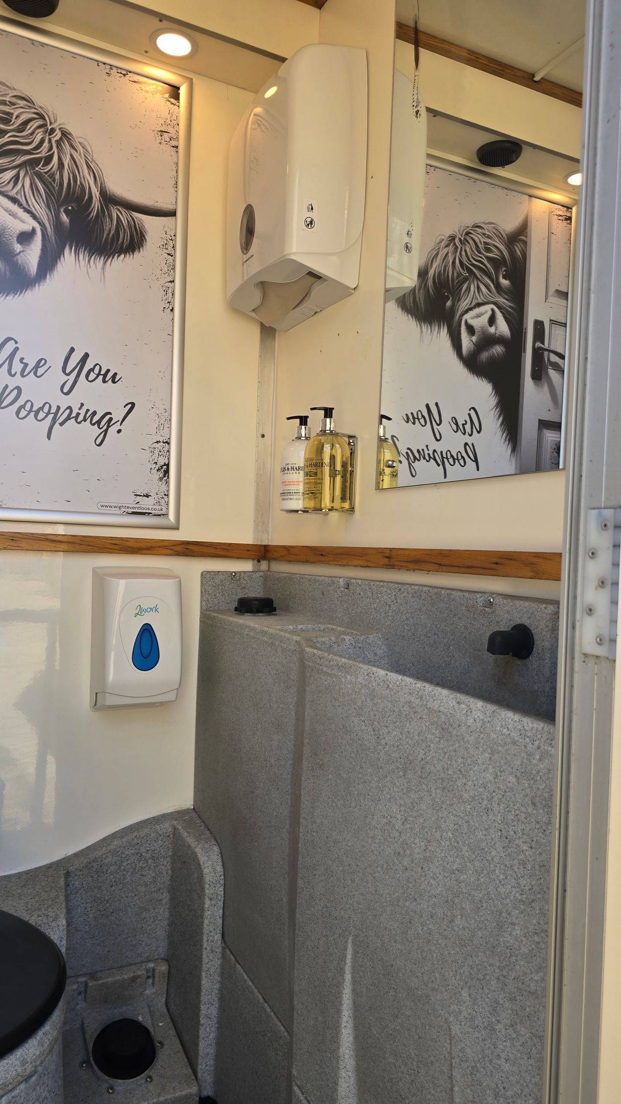 Small bathroom sink area with a mirror, soap dispenser, and two framed wall prints.