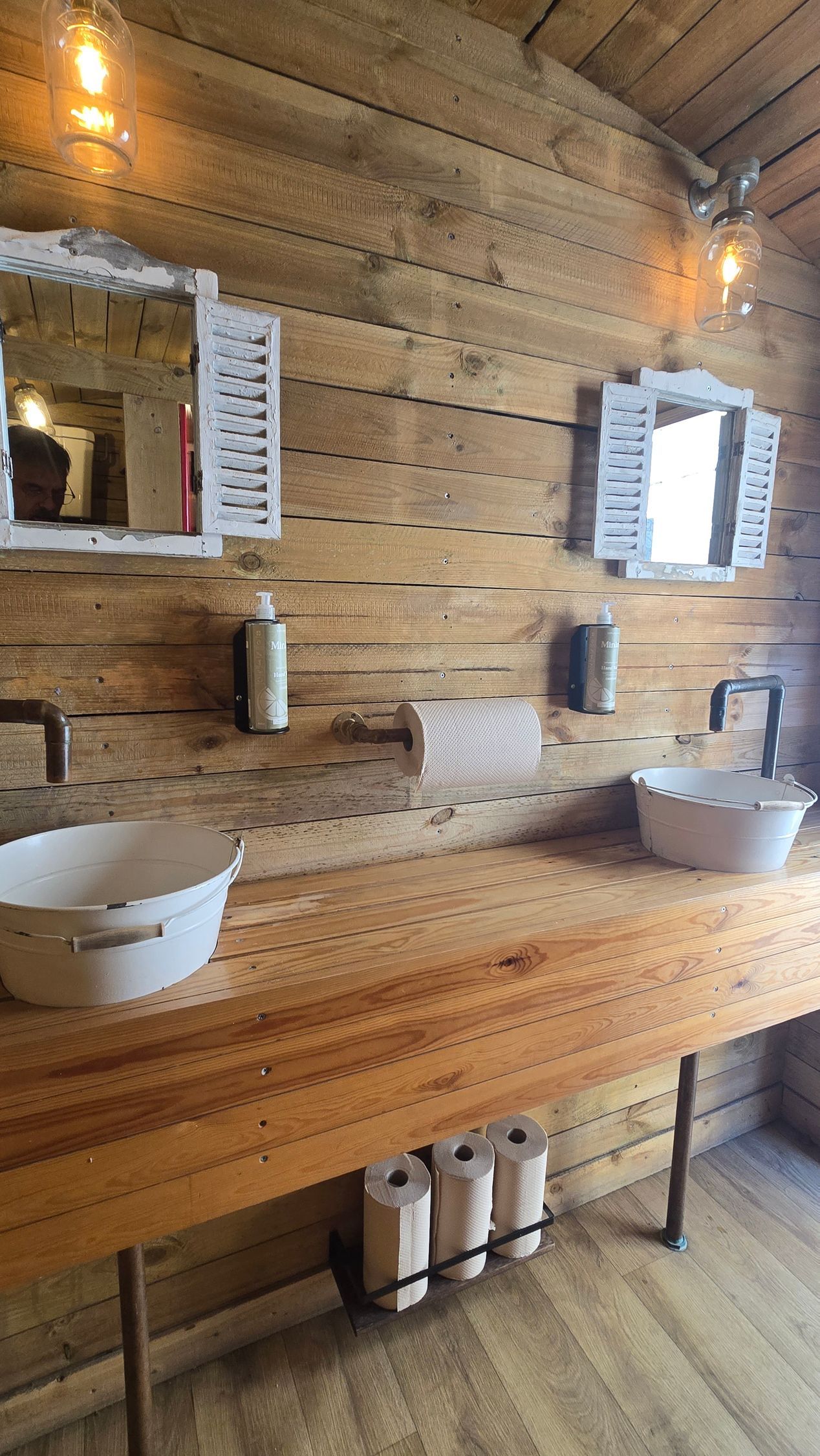 Rustic wooden bathroom with two mirrors, double sinks, and a bench-style counter.
