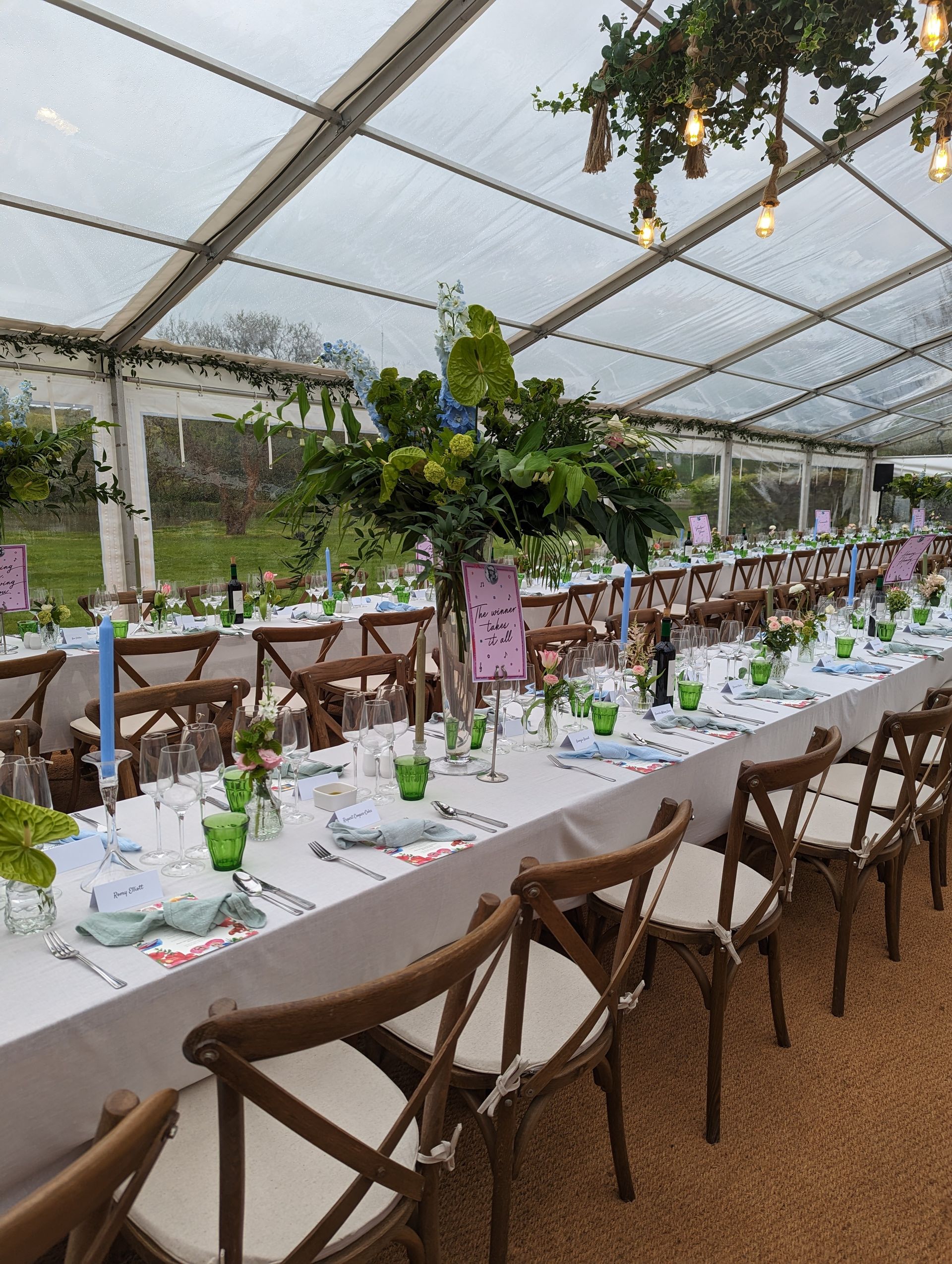 A long table with a clear roof is set up for a wedding reception.
