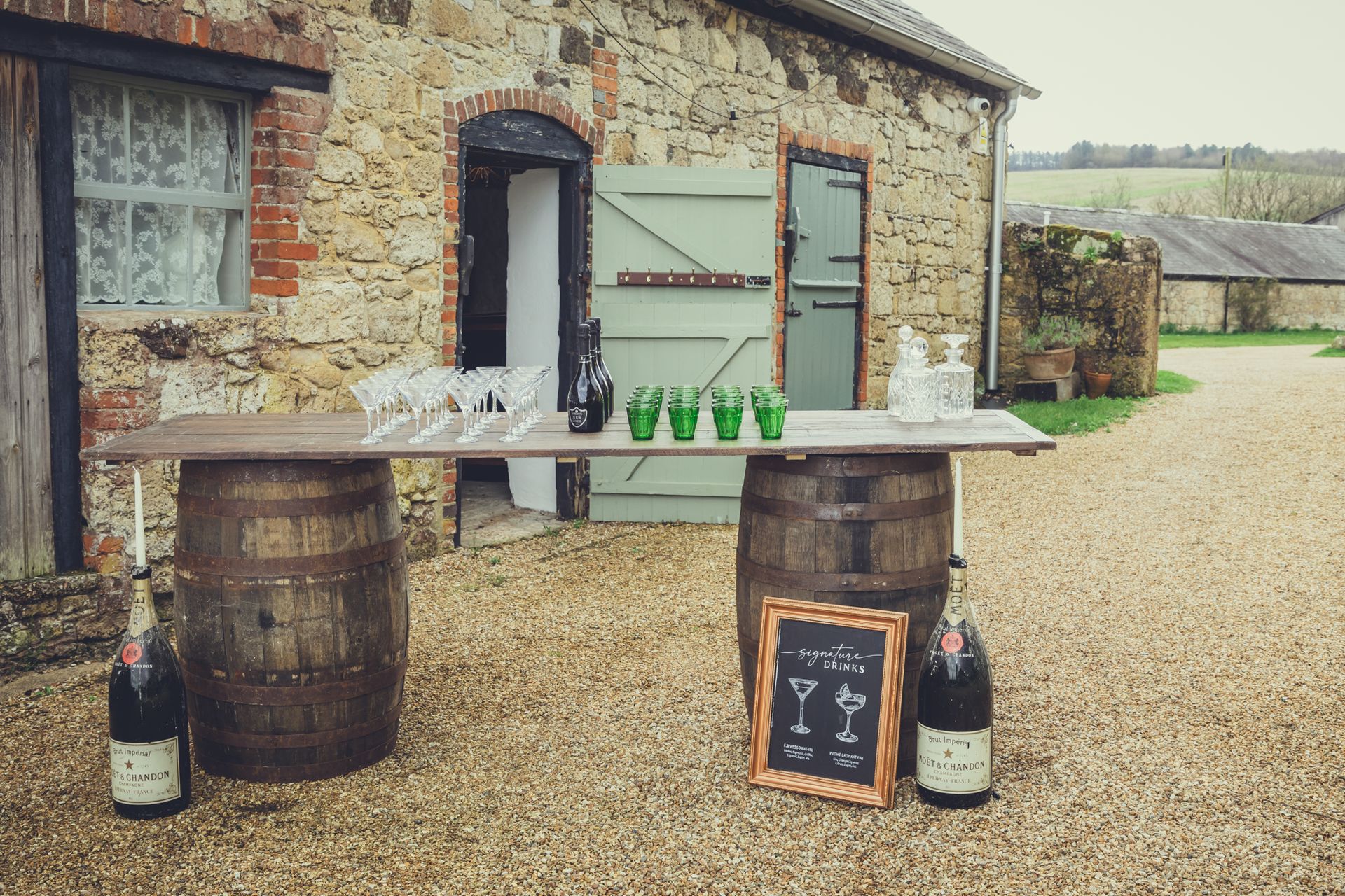 A bar made out of wooden barrels is sitting in front of a stone building.