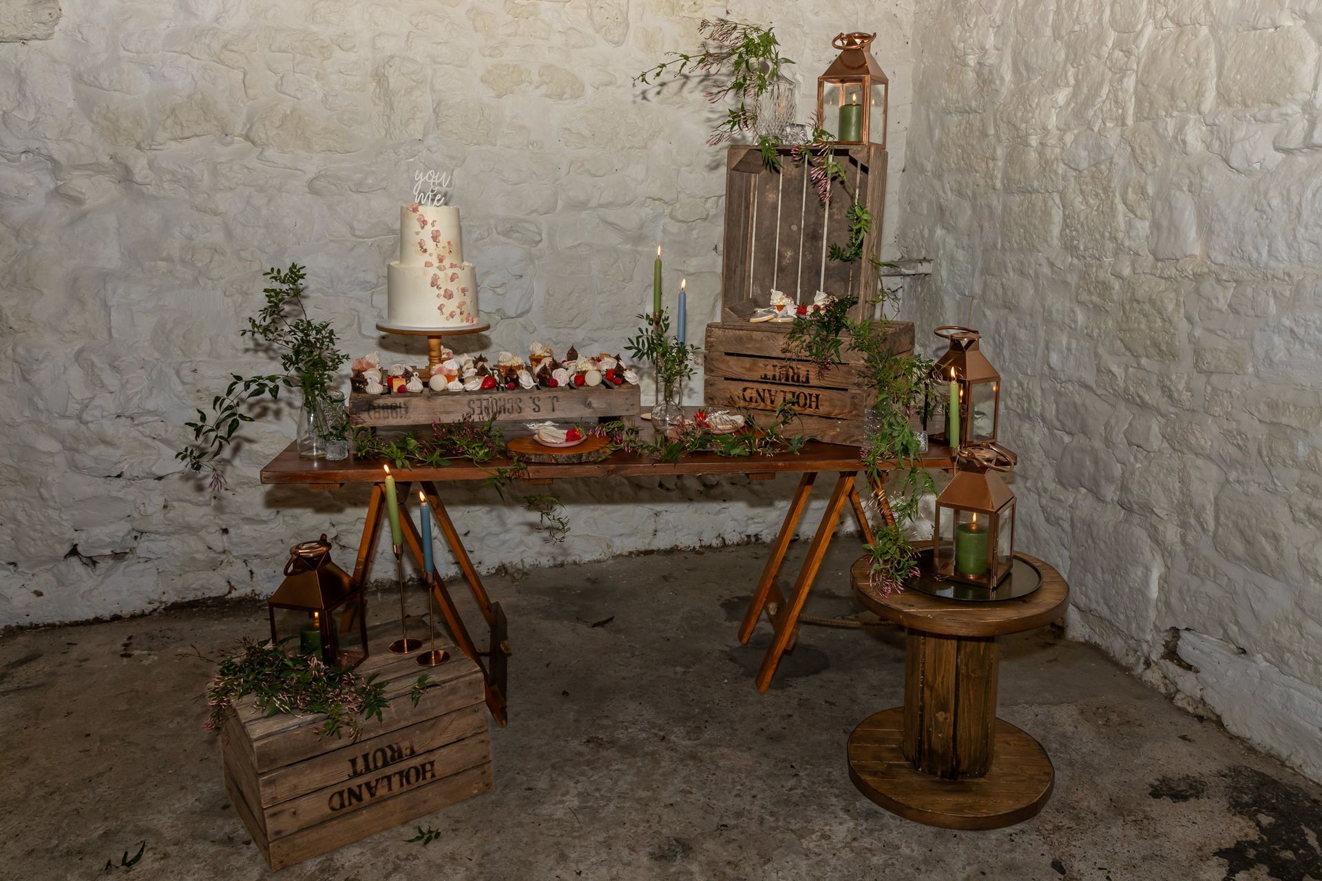A wooden table with a cake and candles on it in a room.