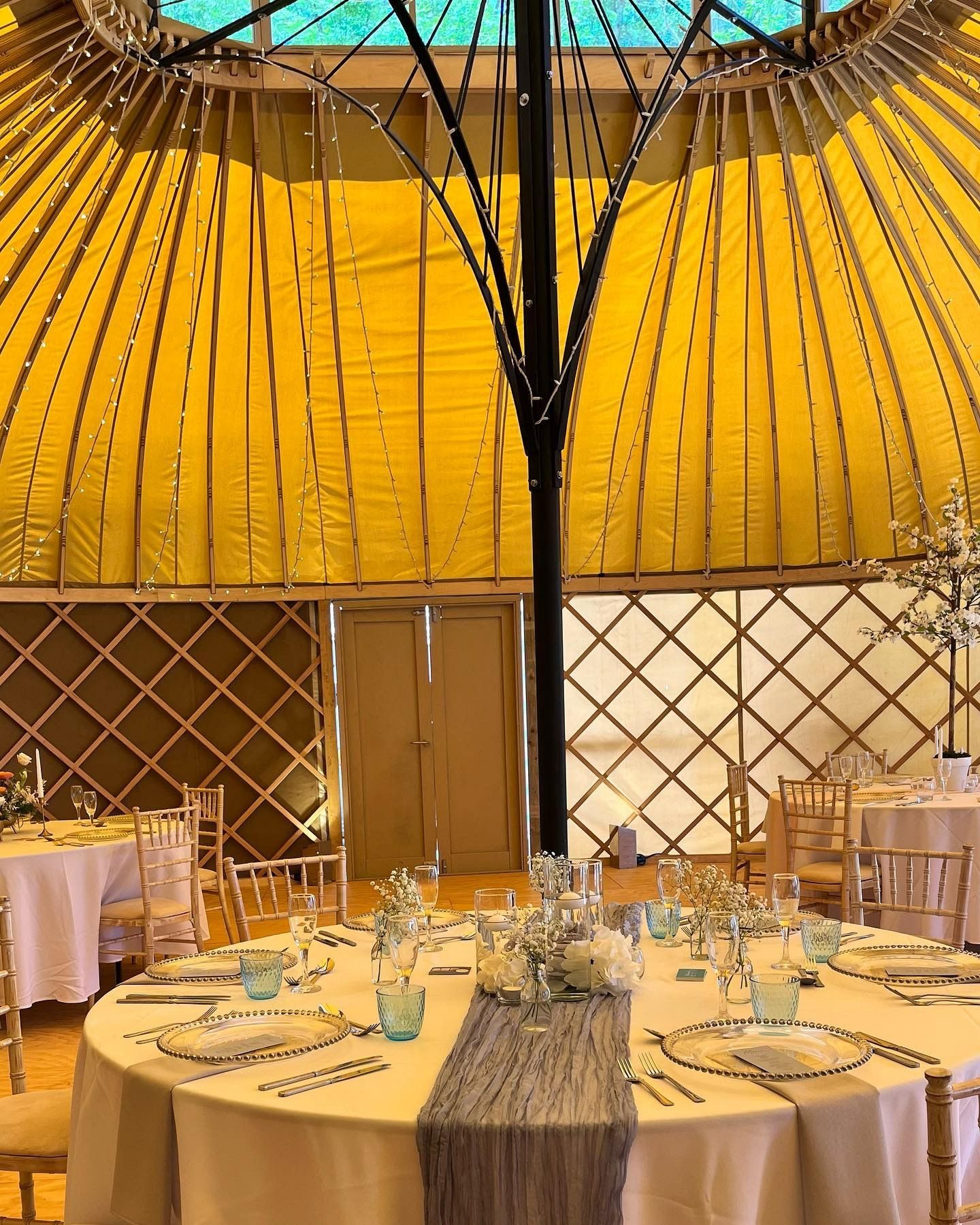 A yurt with tables and chairs set up for a wedding reception