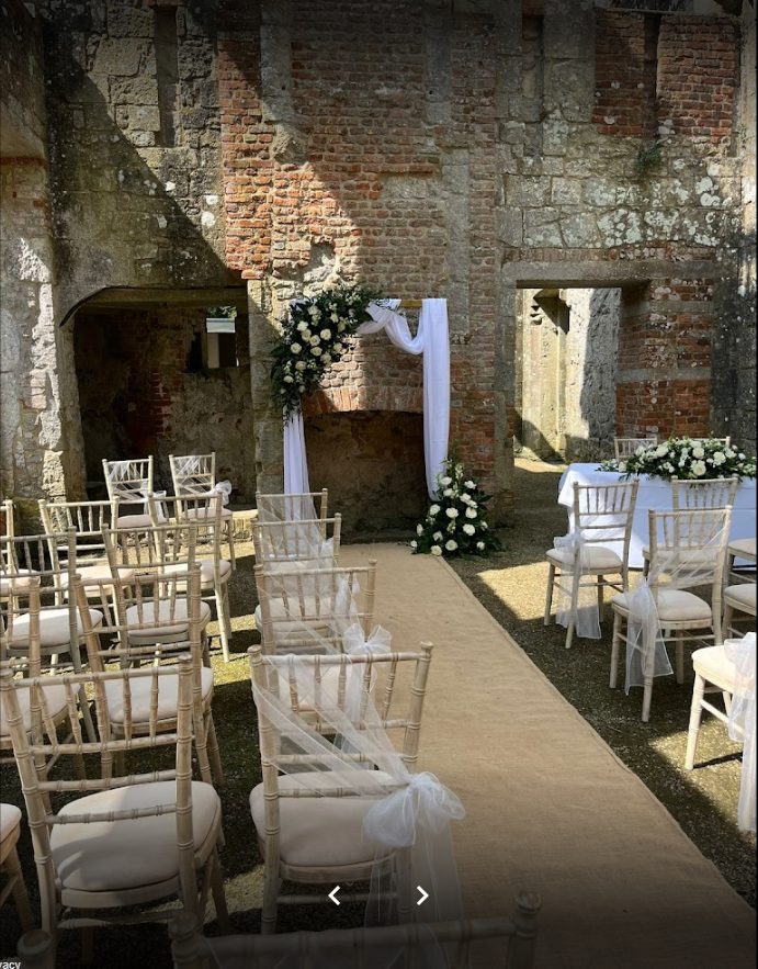 A row of chairs are lined up in front of a brick wall for a wedding ceremony.