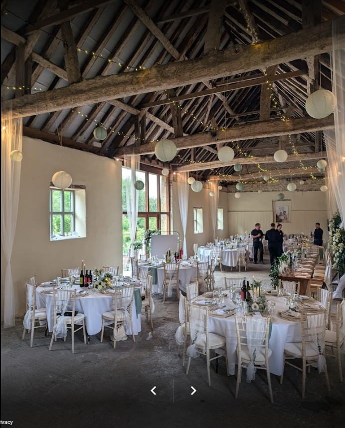 A large room with tables and chairs set up for a wedding reception