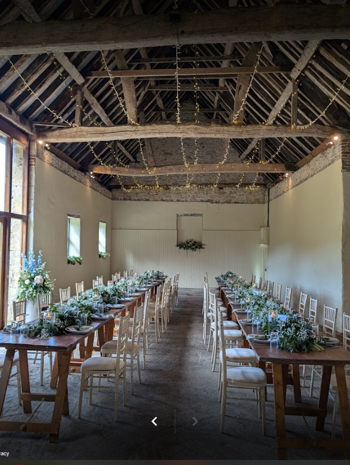A large room with tables and chairs set up for a wedding reception.