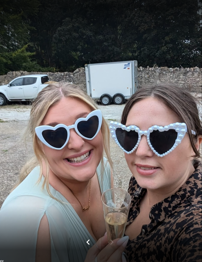 Two women wearing heart shaped sunglasses are posing for a picture