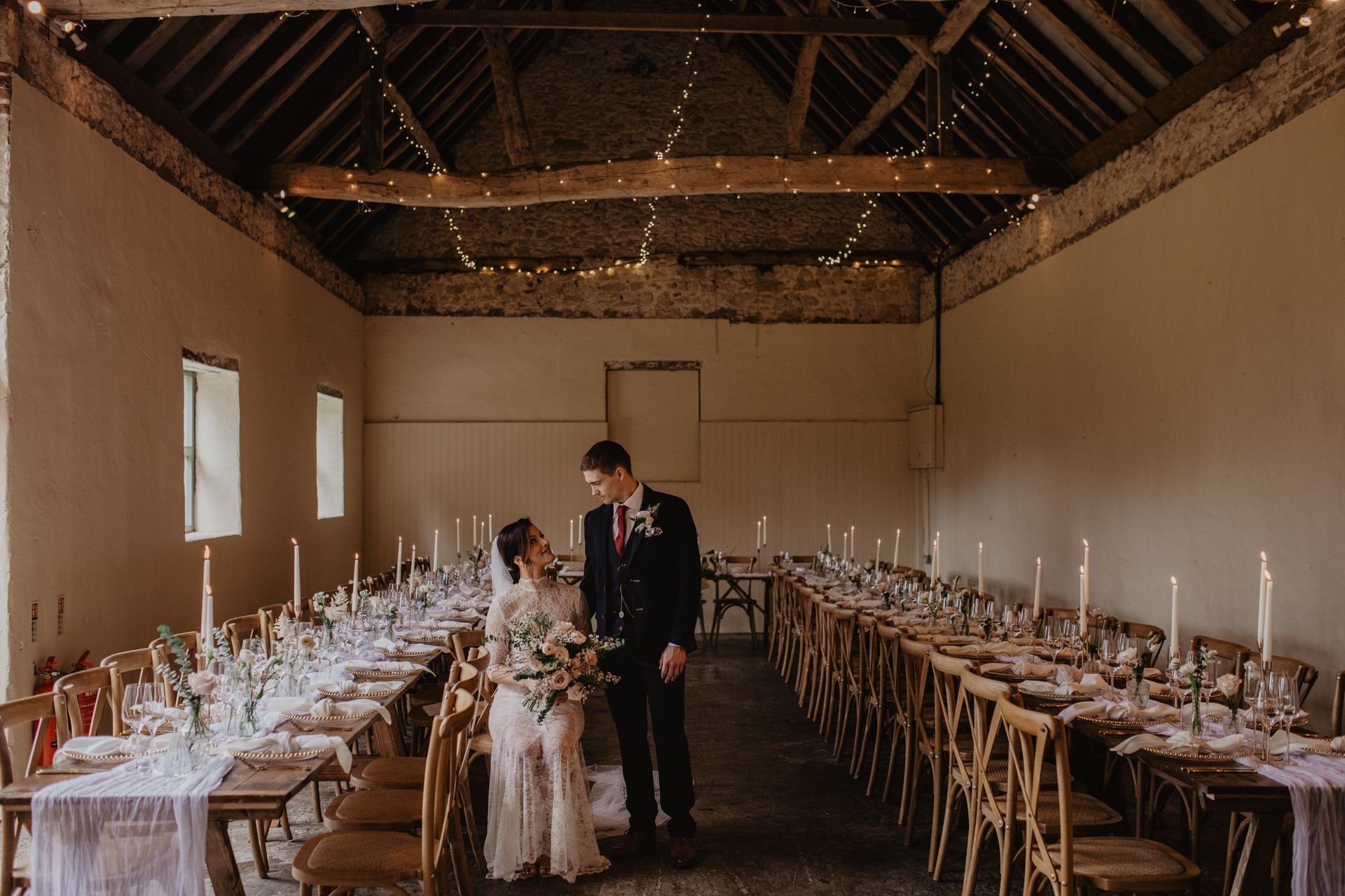 A bride and groom are standing in a large room with tables and chairs.