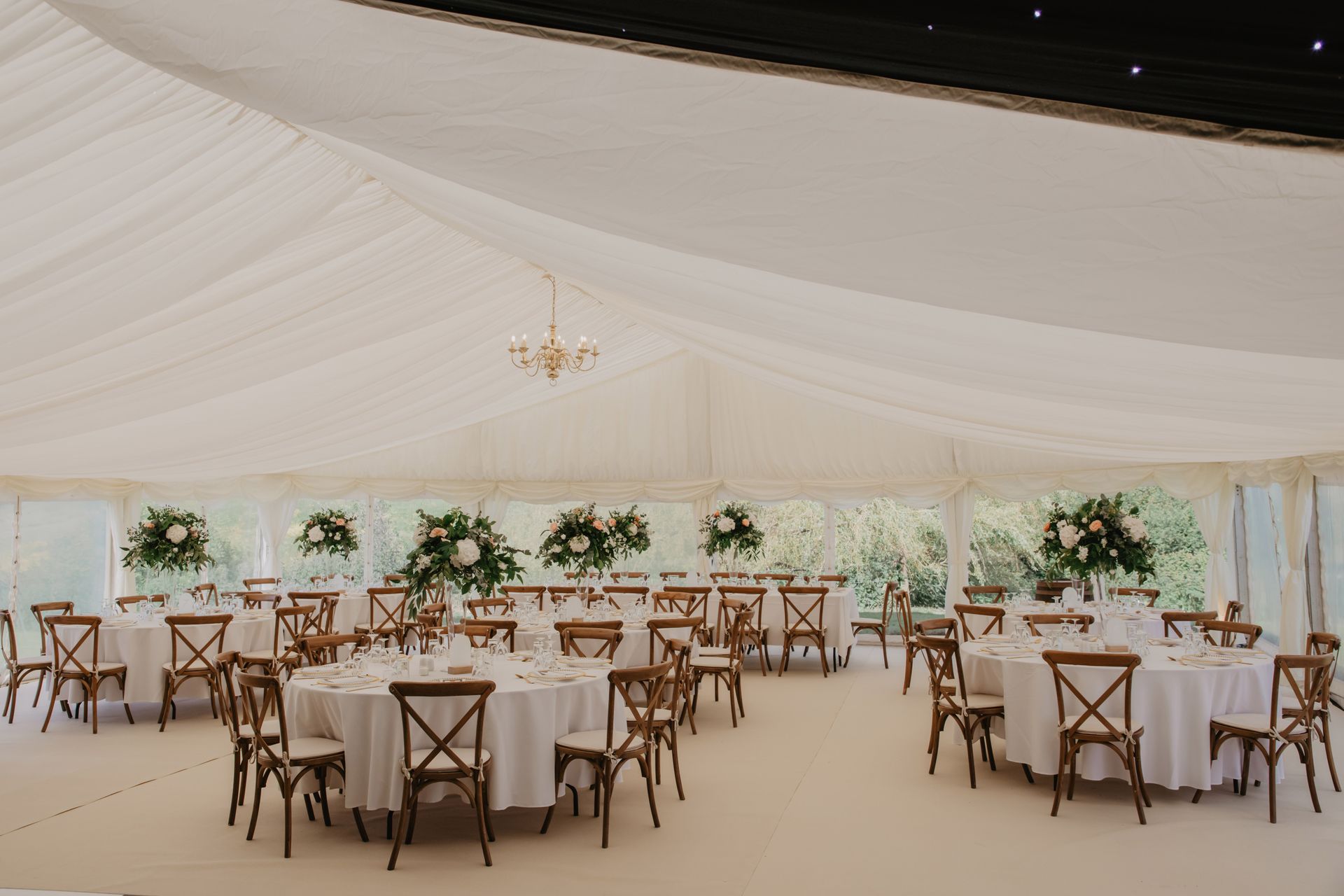 A large tent with tables and chairs set up for a wedding reception.