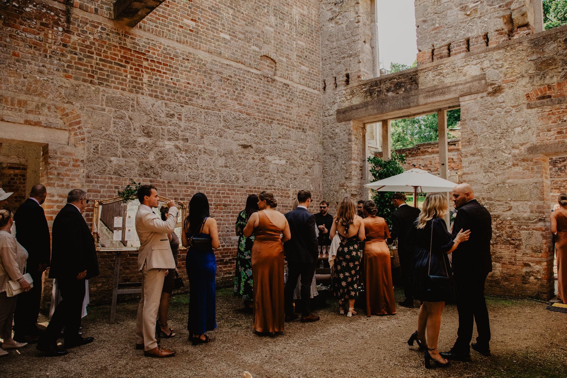 A group of people are standing in front of a brick wall.