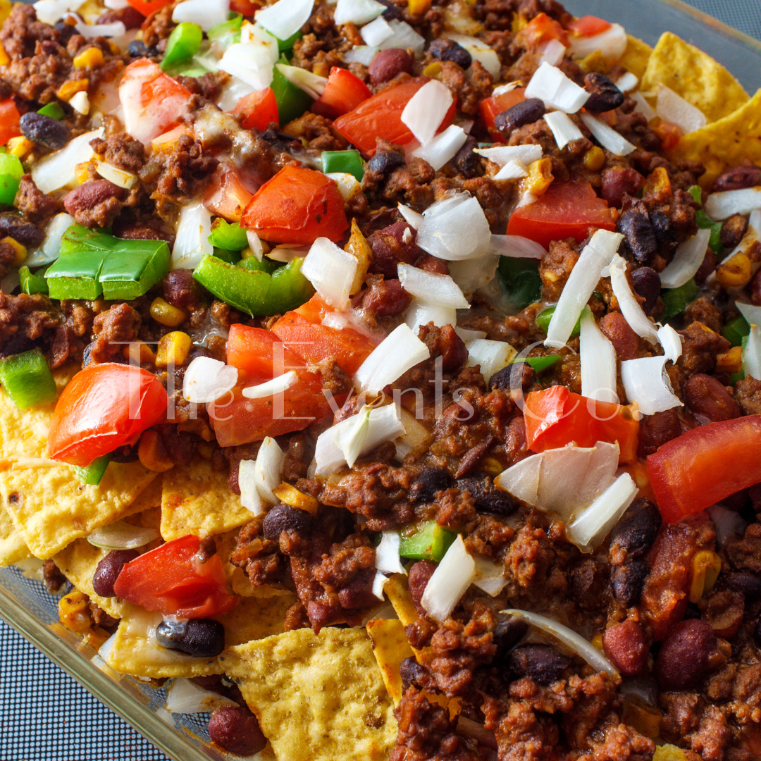 A casserole dish filled with nachos beans tomatoes and onions