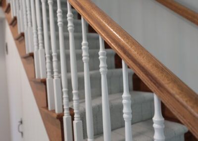 A staircase with white railings and a wooden handrail