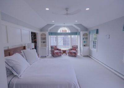 A bedroom with a large bed , chairs , and a ceiling fan.