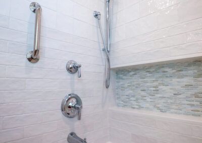 A bathroom with a shower , tub , and handrails.