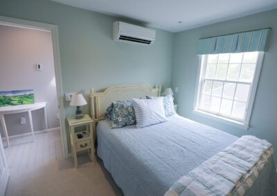 A bedroom with a bed , nightstand , lamp and window.
